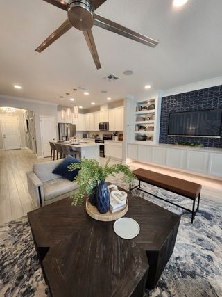 Modern living space with open layout, sleek kitchen, geometric wall design, and cozy seating.