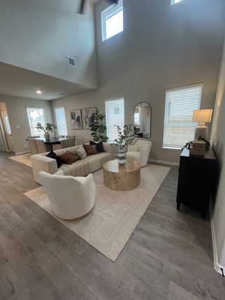 Model Home A cozy living room with high ceilings, stylish furniture, and natural light filtering through large windows.