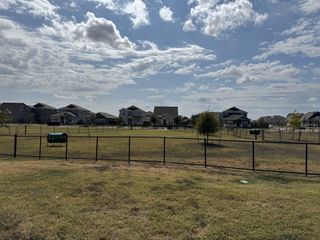 A spacious fenced dog park with open green space, perfect for pets to run and play in Durango Farms by Meritage Homes (Hutto, TX)