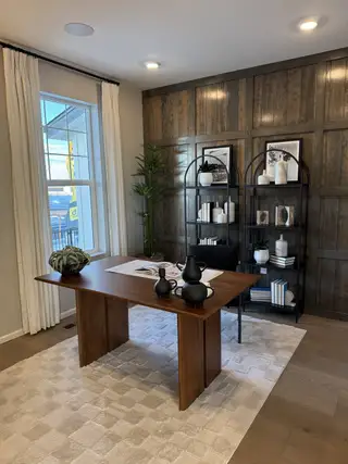 A sophisticated home office with a sleek wooden desk, stylish shelving, and elegant decor on a plush, textured rug.