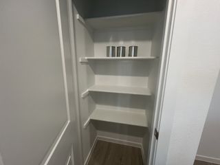 A spacious walk-in pantry with white shelves and a wood floor, perfect for organized kitchen storage.
