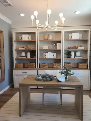 A cozy home office with built-in shelving, a sleek wooden desk, and a modern chandelier.
