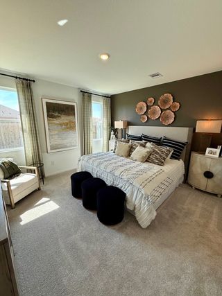 A cozy bedroom featuring a textured accent wall, elegant bedding, and ample natural light through large windows.