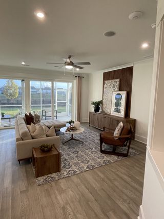 A cozy living room with sleek wood flooring, a modern sofa, and large windows offering natural light.