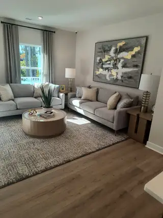 Model Home A cozy living room with stylish gray sofas, abstract art, and a round coffee table on a textured rug.