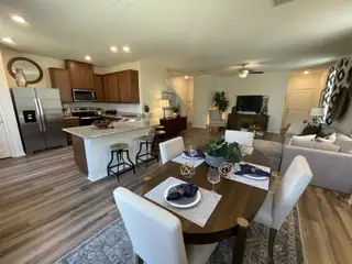 A warm and inviting open-concept living space in a Villas at Presidio home, featuring a dining area with an oval table, a modern kitchen with stainless steel appliances, and a comfortable living room (San Antonio, TX).