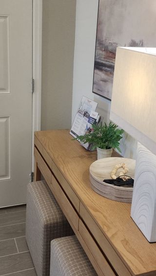 A cozy entryway with a wooden console, abstract art, and soft lighting, featuring decor accents and a potted plant.