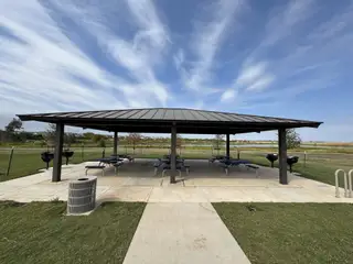 A charming outdoor pavilion with picnic tables and grills in Bryson by Highland Homes, Leander, TX.