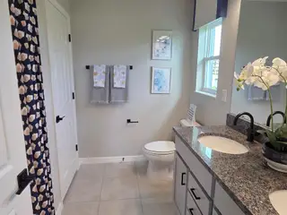 Model Home A bright bathroom with granite countertops, floral accents, and chic fixtures.