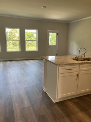 A bright, open space featuring large windows, wood flooring, and a granite kitchen island with modern fixtures.