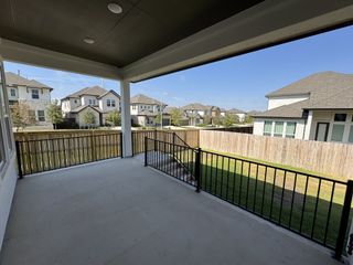 A spacious covered patio overlooking a fenced backyard in a suburban neighborhood.
