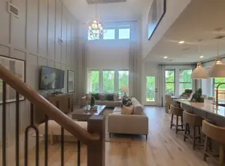 A spacious living area with tall ceilings, large windows, and elegant furnishings, creating a bright and welcoming atmosphere.