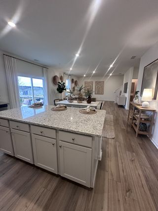 Model Home A modern kitchen with granite island, sleek lighting, wood floors, and stylish decor accents.