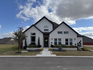 A charming white brick home with a manicured lawn in Sauls Ranch East by Coventry Homes (Round Rock, TX).