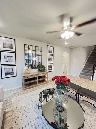 A cozy living room with framed art, a mirrored coffee table, elegant decor, and a ceiling fan.
