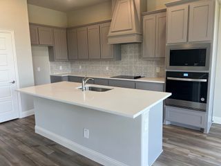 A modern kitchen with sleek gray cabinetry, a spacious island, and wood flooring for a contemporary feel.