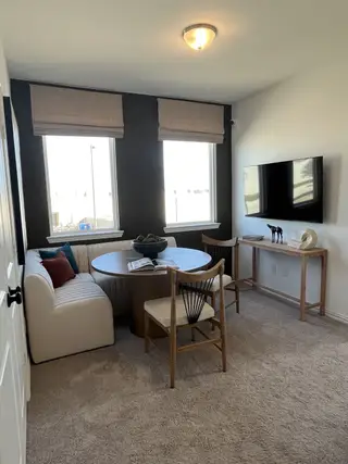 Cozy nook with a round table, cushioned bench, accent chairs, and wall-mounted TV, ideal for relaxation or casual dining.