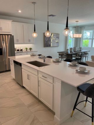 A modern kitchen with sleek white cabinets, pendant lighting, and a spacious island perfect for dining and entertaining.