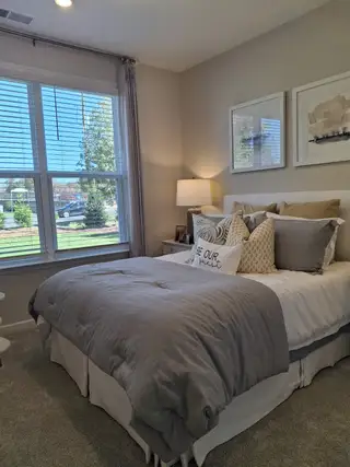 A cozy bedroom featuring plush bedding, soft carpeting, and large windows for ample natural light.