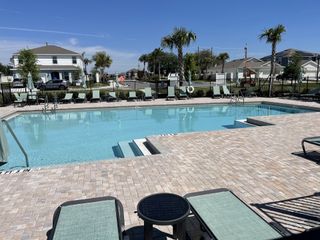 A sparkling resort-style pool with lounge chairs and palm trees, offering relaxation in Winding Meadows by Pulte Homes (Apopka, FL).