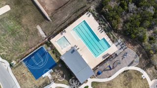 Community Amenities An aerial view of the Crescent Bluff recreational area by Scott Homes (Georgetown, TX), featuring a pool, sports court, playground, and walking paths.