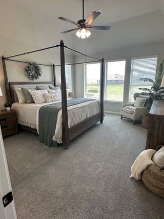 A cozy bedroom featuring a four-poster bed, neutral tones, and large windows offering ample natural light.