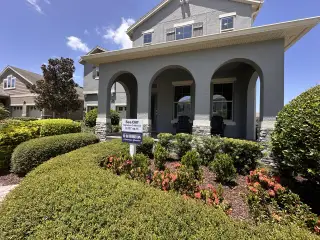 A charming gray home with arched entry and lush landscaping in Waterleigh by D.R. Horton (Winter Garden, FL).
