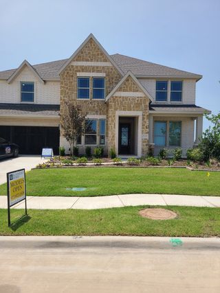 Street view A beautiful stone-brick home with manicured landscaping in Stone River Glen 60s by Bloomfield Homes (Royse City, TX).