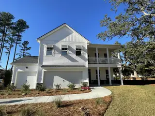 Street view Charming white clapboard home with a wraparound porch in The Oaks by Beazer Homes, Goose Creek, SC.