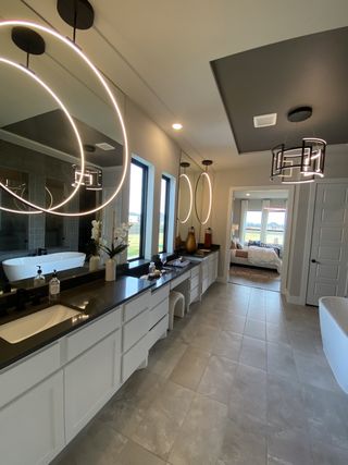 A luxurious bathroom featuring elegant double vanities, large mirrors, sleek pendant lights, and a stunning freestanding tub.