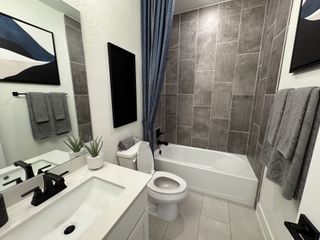 A modern bathroom with gray tile, sleek black fixtures, and stylish artwork, creating a clean, contemporary feel.