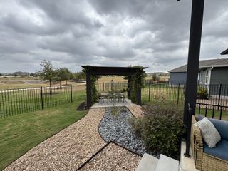 A peaceful backyard with a pergola and seating area at Urban Courtyard Homes at Easton Park by Brookfield Residential (Austin, TX).