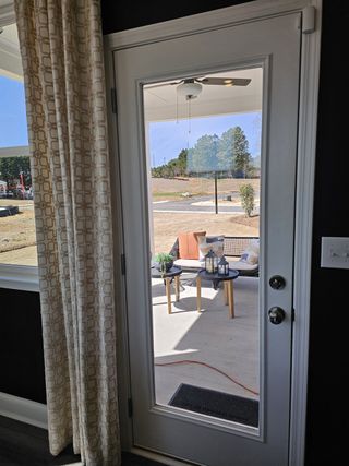 A chic patio view through a glass door, featuring outdoor seating, a table, and elegant drapes.