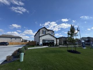 A modern model home with a well-manicured lawn and inviting curb appeal in Crosswinds by Pulte Homes (Kyle, TX).