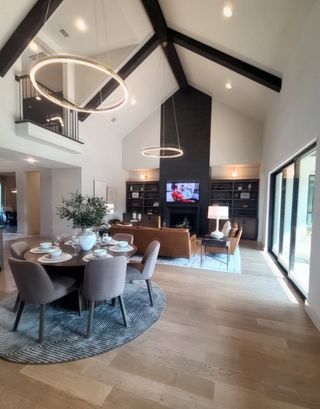 An elegant living space with high ceilings, modern lighting, wooden floors, and cozy seating.