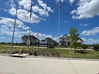 A beautiful community entrance with modern homes under blue skies in Trillium 60s by Taylor Morrison (Richmond, TX).