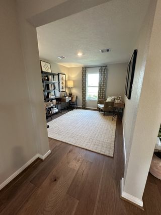 A cozy office nook with a plush armchair, elegant bookshelf, and abundant natural light.