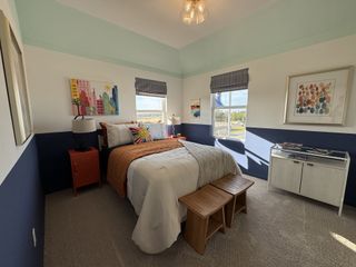 Model Home A cozy bedroom with colorful wall art, a modern lamp, and ample natural light illuminating the room.