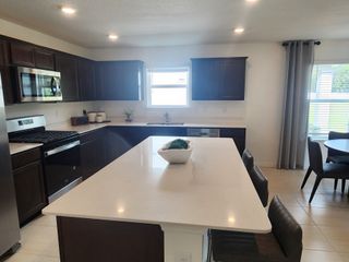 A modern kitchen with dark wood cabinetry, a sleek island, and stainless steel appliances.