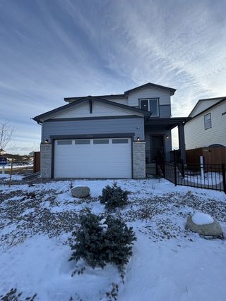 A contemporary gray home with a snowy yard in Farmlore by Century Communities (Brighton, CO).