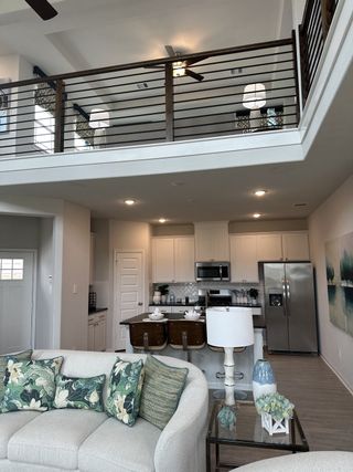 An airy living room with a loft view, modern kitchen, and stylish decor.