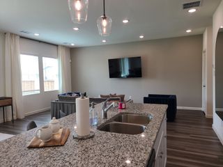 Modern living space with granite island, cozy seating, wood flooring, and sleek lighting for a welcoming atmosphere.