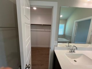 A sleek bathroom featuring a modern sink, large mirror, and an open walk-in closet with ample storage space.
