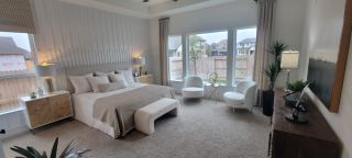 Model Home A serene master bedroom with neutral tones, plush carpeting, and large windows, creating a tranquil retreat in a Stillwater Ranch home by Coventry Homes (San Antonio, TX).
