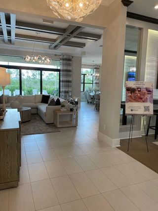 A modern living area with sleek tile floors, contemporary lighting fixtures, and large windows overlooking greenery.