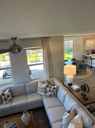 Model Home A cozy living area with a spacious grey sectional sofa, geometric pillows, and a view into a stylish open dining space.