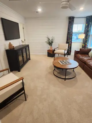 A cozy living area with shiplap walls, plush seating, a round coffee table, and a wall-mounted TV for a relaxed vibe.