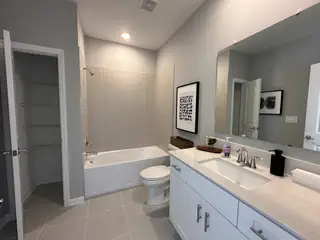 A modern bathroom featuring a sleek vanity, spacious tub, and elegant neutral tiles, creating a serene and stylish ambiance.