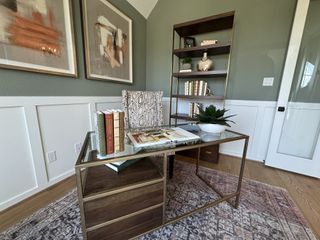 A chic home office with modern art, a glass desk, stylish chair, and a sleek shelving unit.