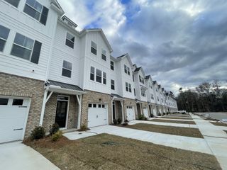 Street view Charming white townhomes with brick accents in Village Club at Wescott by Ashton Woods, Summerville, SC.
